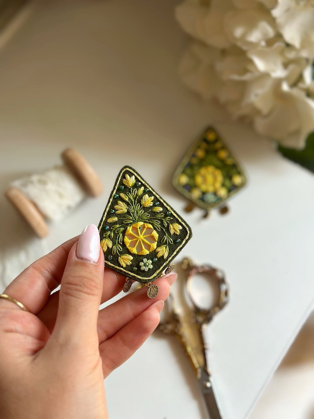 Broche brodée Yalda verte et jaune, tenue à la main